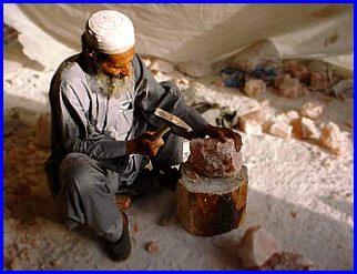 Picture of a worker with a hammer cutting to shape a lump of salt